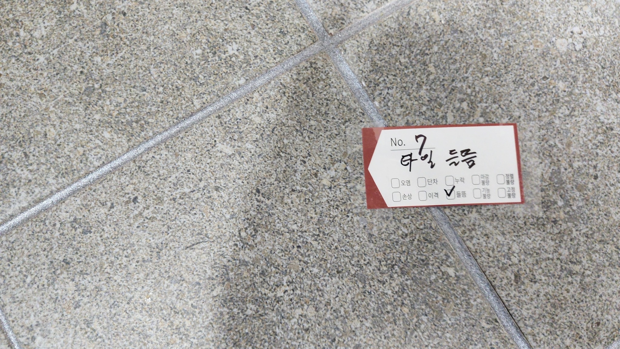 욕실 바닥 타일 들뜸으로 기록된 현장 사진입니다. 사진과 기록된 위치를 함께 전달해 보수 범위를 확인하도록 권합니다.